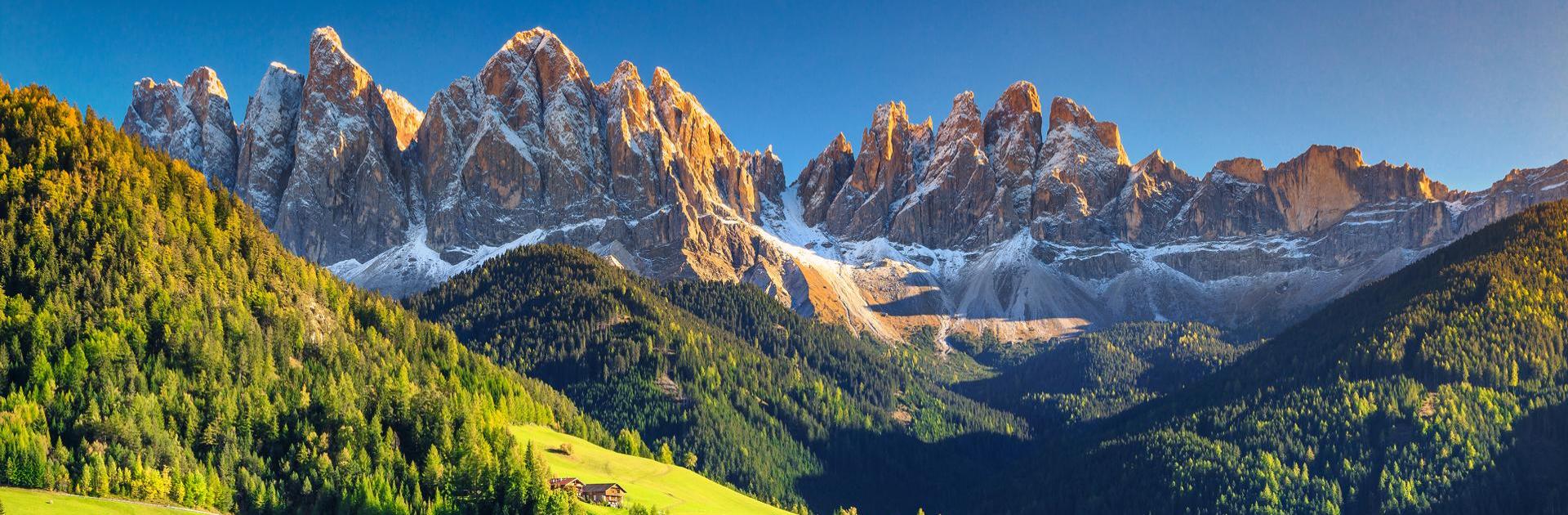 Panorama di un lago alpino con un villaggio e montagne sullo sfondo.